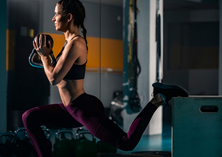 woman performing bulgarian split squat with kettlebell upper glute exercise