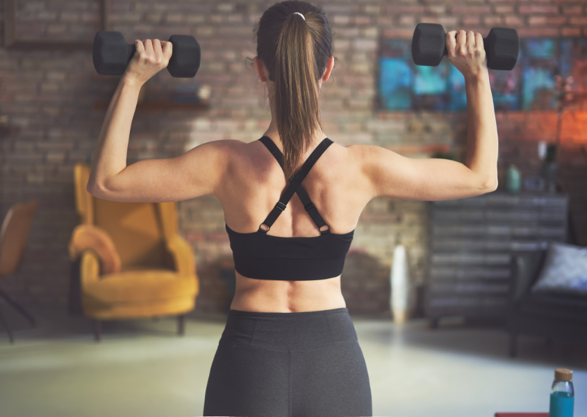 woman in fitness wear carrying dumbbells